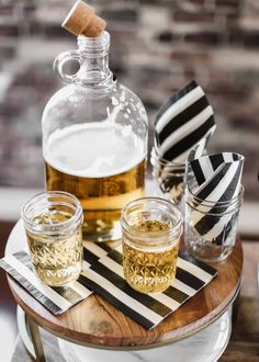 three glasses and a bottle on a table with black and white striped napkins next to them