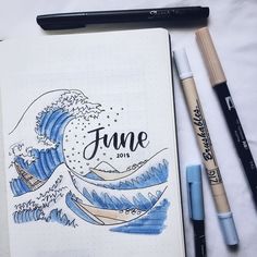 an open notebook with the word june written on it next to some markers and pens