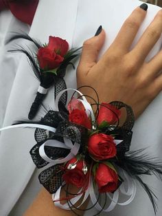 two red roses and black feathers are on the wrist of a woman wearing a white shirt