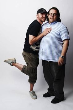 two men standing next to each other in front of a white background