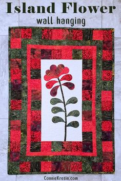 a quilted wall hanging with a red flower on it and the words island flower