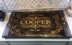 a black and gold sign that says cooper est 1911 on the side of a kitchen counter