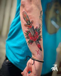 a person with a tattoo on their arm holding a knife and cross in the other hand