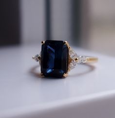 a close up of a ring with a blue stone and two white stones on it