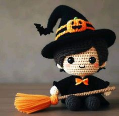 a crocheted doll is holding a broom and wearing a black hat with a pumpkin on it