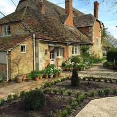 an old brick house with garden beds in the front yard