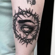 a black and white photo of a woman's eye in a crown of barbed wire