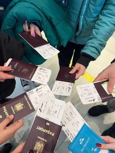 several people are holding their passports in the middle of a table with other people around them