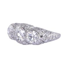 This is part of Chairish’s Fine Jewelry assortment.  Vintage Art Deco three center diamond platinum ring, circa 1930. This Art Deco platinum ring features three bezel set center diamonds, including a .95 carat VS1 G, a .66 carat VS2 H, and a .68 carat VS2 H. There are also 68 accent diamonds including four old European cut diamonds at .14 carat total weight and 64 single cuts at .84 carat total weight. All accent diamond have VS1-2 clarity and G-I color, with one I1. The diamonds come to a grand Art Deco Three Stone Platinum Jewelry, Art Deco Three Stone Diamond Ring, Heirloom Three Stone Platinum Ring, Heirloom Platinum Three Stone Ring, Heirloom Platinum Three-stone Ring, Heirloom Three-stone Platinum Ring, Platinum Three Stone Diamond Ring Fine Jewelry, Classic Platinum Three-stone Ring, Three Stone Platinum Diamond Ring Fine Jewelry