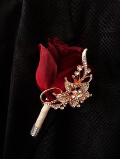 a red rose brooch sitting on top of a black jacket with crystal stones and pearls