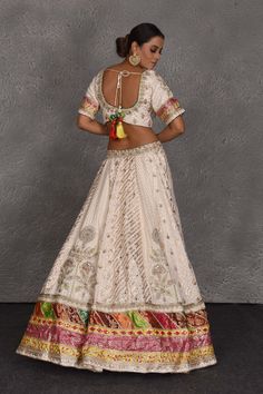 Be the center of attraction at weddings in this exquisite cream embroidered lehenga with multicolor border. It comes with a beautiful multicolor dupatta. DISCLAIMER: The actual product may vary slightly from the image. These are custom orders, hence expect slight variation in color and placement of the motif or buta. ESTIMATED DELIVERY: Because this is a custom order, it would take about 4 weeks from the date of purchase. RETURN POLICY: This product is a custom order and cannot be returned or ex Anarkali White Set With Meenakari Details, Anarkali White Sets With Meenakari, White Meenakari Sharara For Wedding, White Meenakari Lehenga For Navratri, Festival White Lehenga With Meenakari Details, Festive White Sharara With Meenakari, Festive White Meenakari Lehenga, Navratri White Meenakari Lehenga, White Meenakari Traditional Wear For Reception