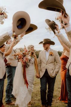 a group of people standing around each other with hats on their heads and bouquets in the air