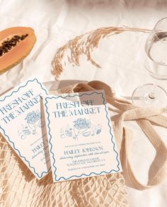 two wedding cards sitting on top of a table next to some wine glasses and a cantaloupe