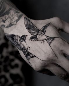 a person's hand with tattoos on it and two birds flying over the palm