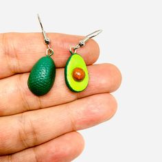 an avocado shaped earrings is being held in someone's hand