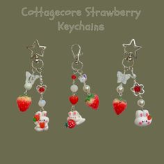 four different charms with strawberrys and cats on them, all hanging from the same keychain