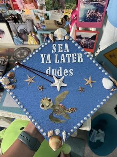 a blue graduation cap with sea ya later dudes written on it and seashells