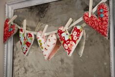 several hearts are hanging on a clothes line in front of a mirror with an old frame