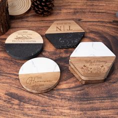 three personalized coasters on top of a wooden table with pine cones in the background