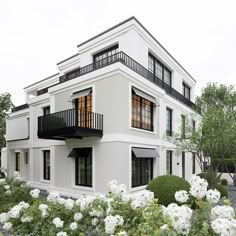 a white house with black balconies and flowers