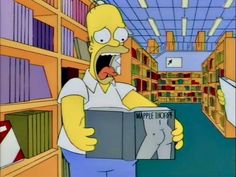 the simpsons is reading a book in a library with his mouth open and tongue out