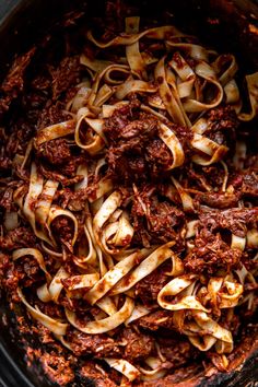 an overhead view of pasta in a slow cooker with meat and sauce on top