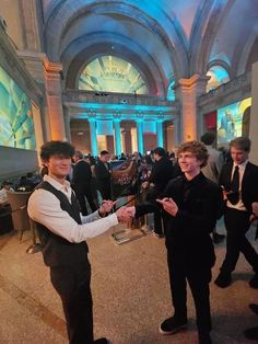 two young men in formal wear standing next to each other at a convention or event