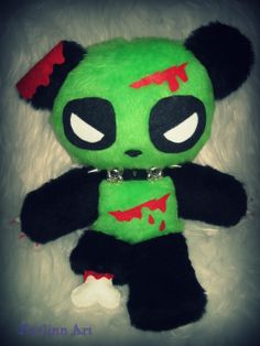 a green stuffed animal with black and red paint on it's face