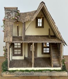 a doll house is shown on a wooden table with white walls and brown trimmings