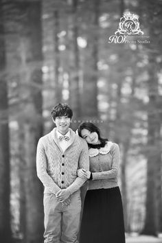 black and white photograph of a couple standing in front of trees with their arms around each other