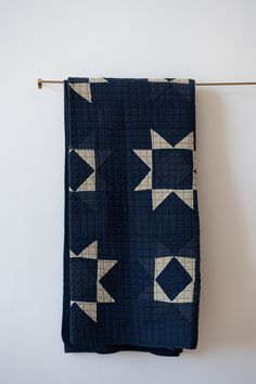 a blue and white quilt hanging on a clothes line with an arrow design in the middle