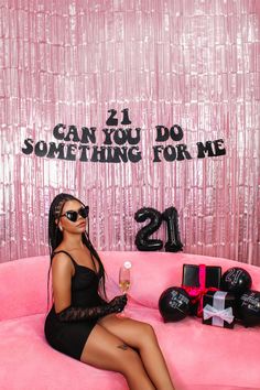 a woman sitting on top of a pink couch in front of a sign that says can you do something for me?