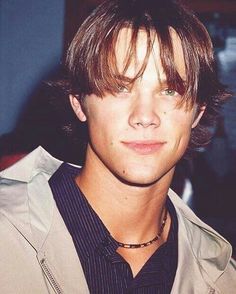 a close up of a person wearing a shirt and tie with his hair pulled back