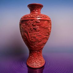 a red vase sitting on top of a purple surface