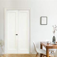 a dining room with white walls and wooden flooring is seen in this image from the doorway