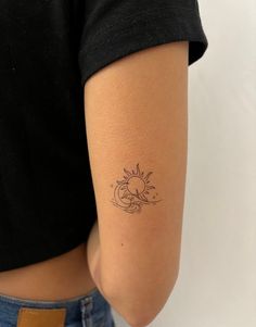 a woman with a sun and moon tattoo on her left arm, behind her is a black t - shirt