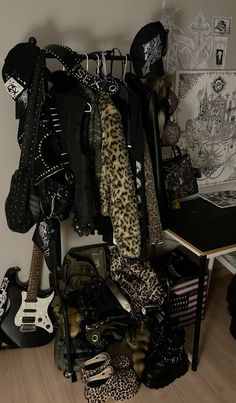 a bunch of clothes and shoes are hanging on the wall next to a table with a guitar