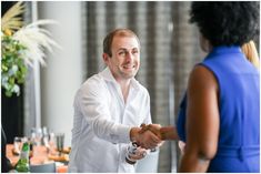 a man shaking hands with a woman at a dinner table