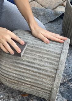 a woman is sitting on the ground with her hand on top of a piece of concrete