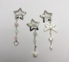 three different types of earrings with charms attached to each earring on a white surface