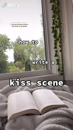 an open book sitting on top of a bed next to a window with the words how to write a kiss scene