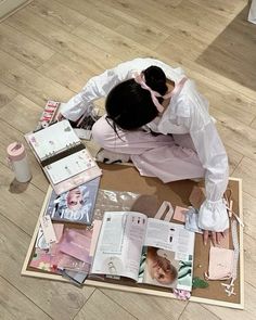 a woman is sitting on the floor with many items around her and looking at them