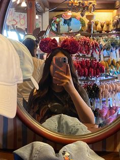 a woman taking a selfie in front of a mirror with hats on her head