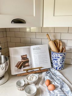 an open book sitting on top of a counter next to bowls and utensils