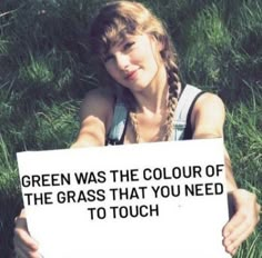 a woman holding a sign that says green was the color of the grass that you need to touch