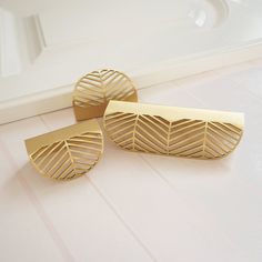 two gold cufflinks sitting next to each other on a white counter top in front of a mirror