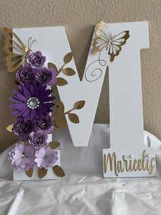 the letter m is decorated with purple flowers and gold foil leaves, along with a butterfly