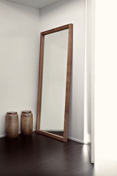 a large mirror sitting on top of a wooden floor next to vases and jars