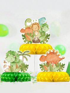 three tiered cake with dinosaurs and plants on top, surrounded by green balloons in the background