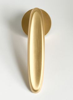 an oval shaped metal object on a white surface with a gold colored handle and base